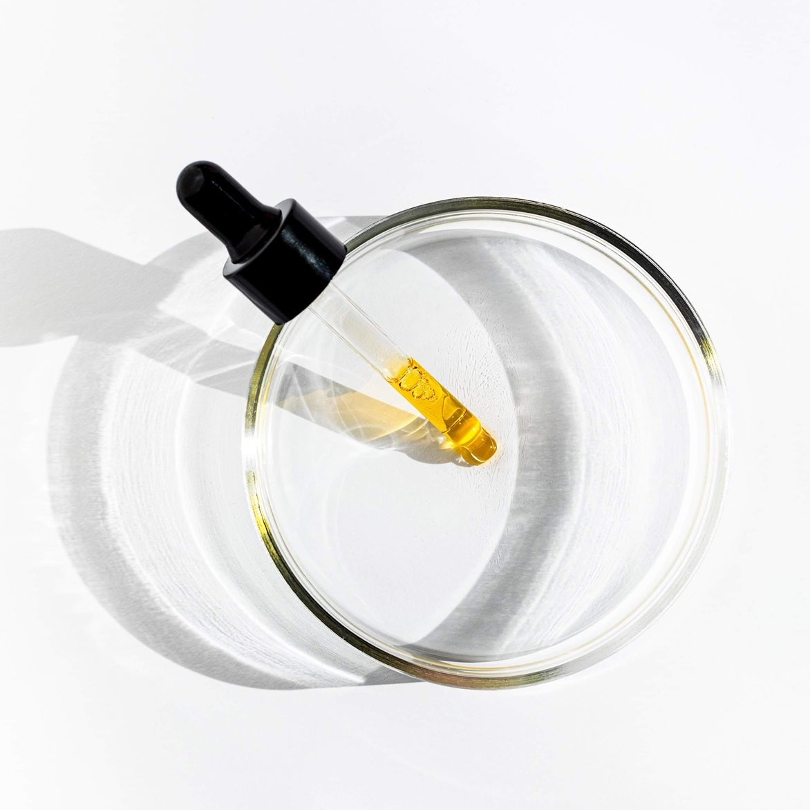 Glass dropper bottle with black cap on a white background