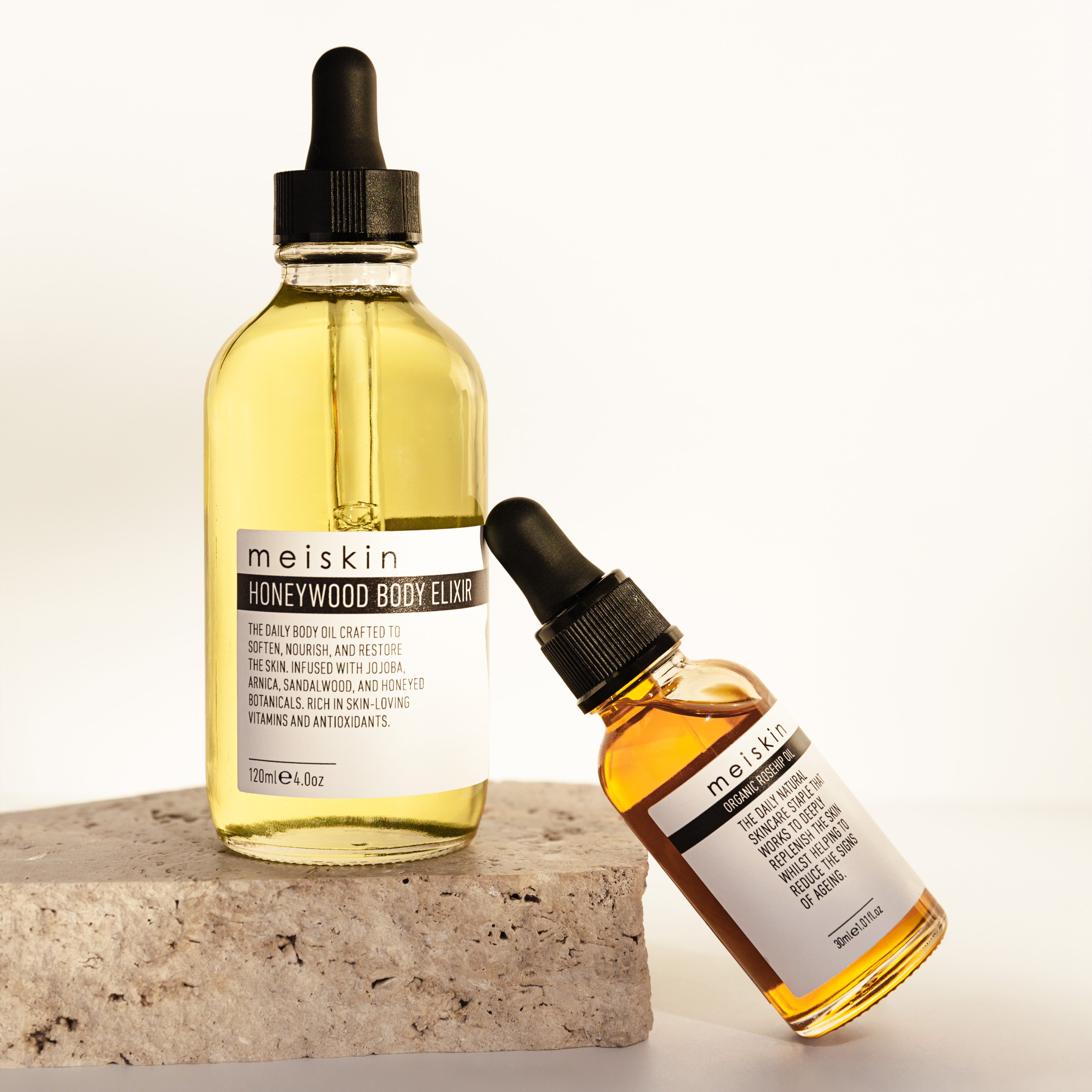 Two bottles of Melvskin Honeywood Body Elixir on a light background