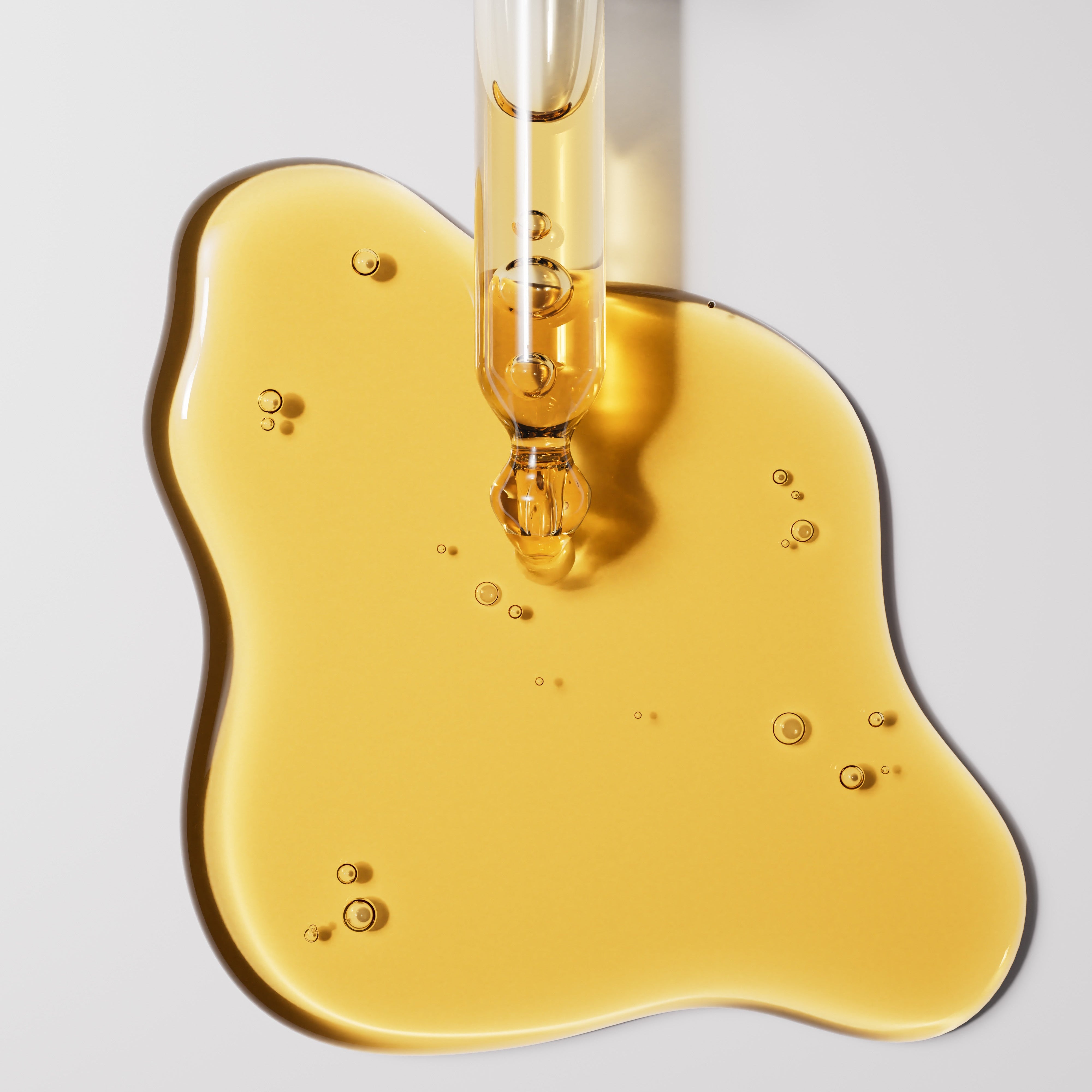 Yellow Meiskin Oil liquid being dripped from a dropper onto a gray surface