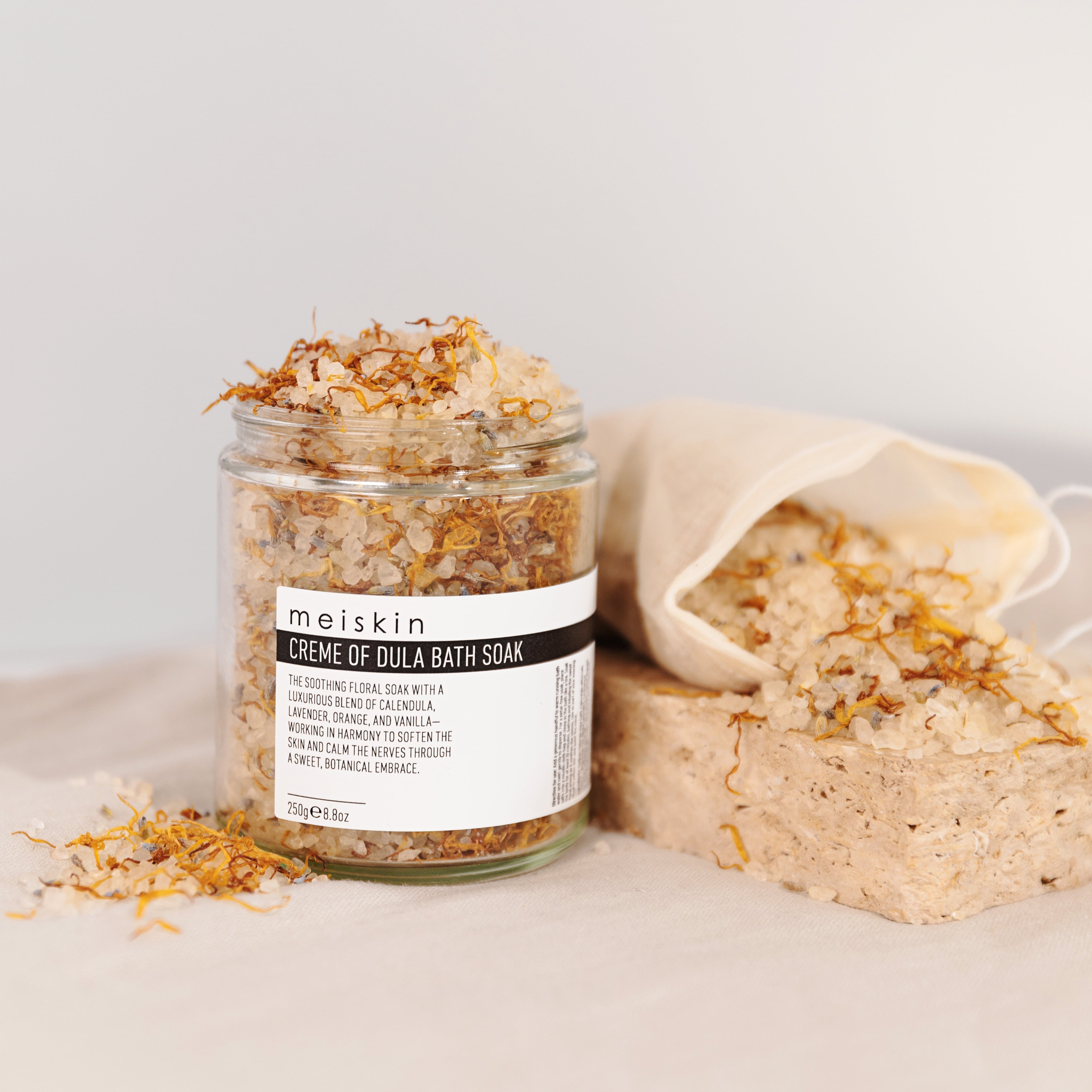 Meiskin Jar of 'Creme de Dula Bath Soak' by meiskin with a bag of bath soak on a light background