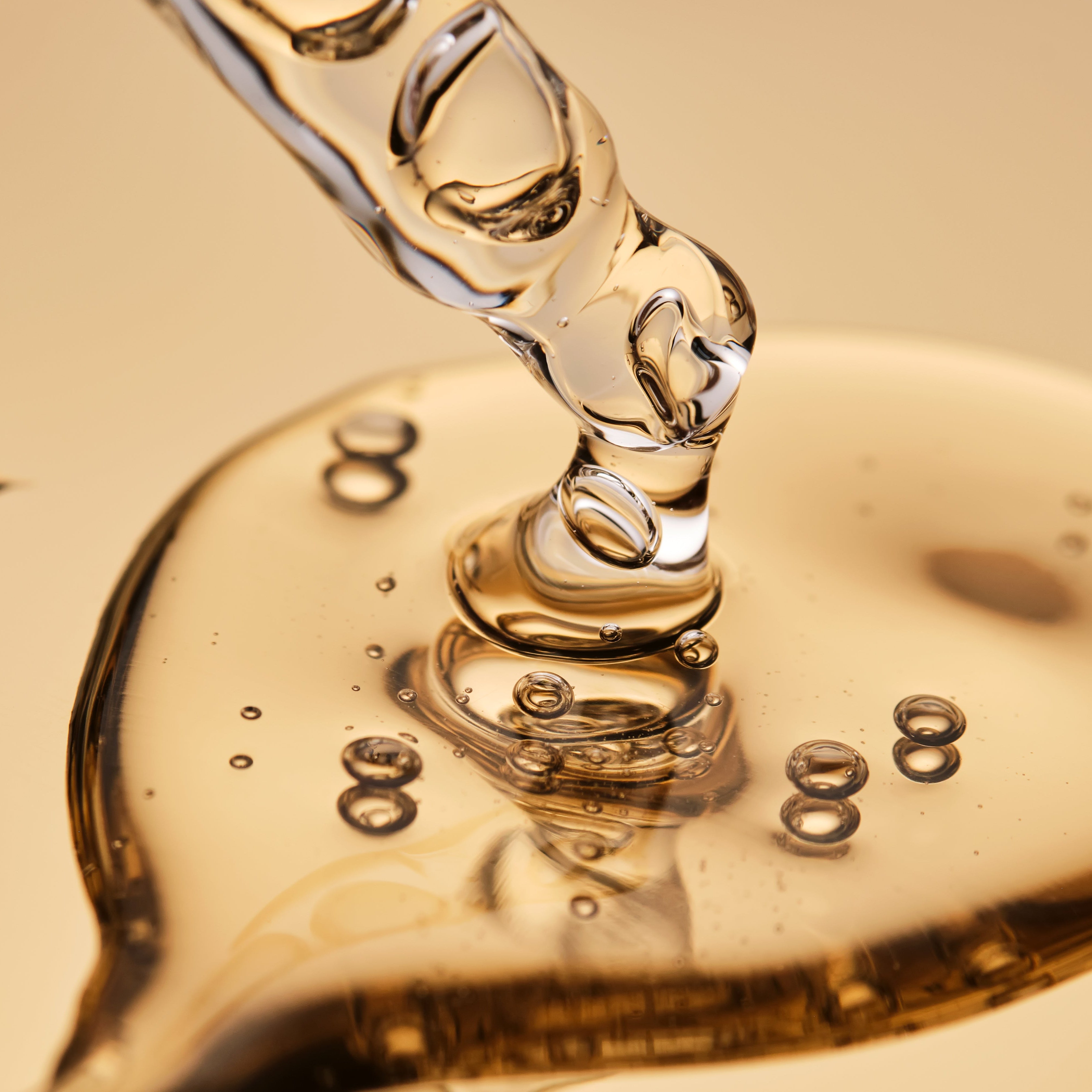 Close-up of a heart-shaped pool of oil with a dropper on a beige background