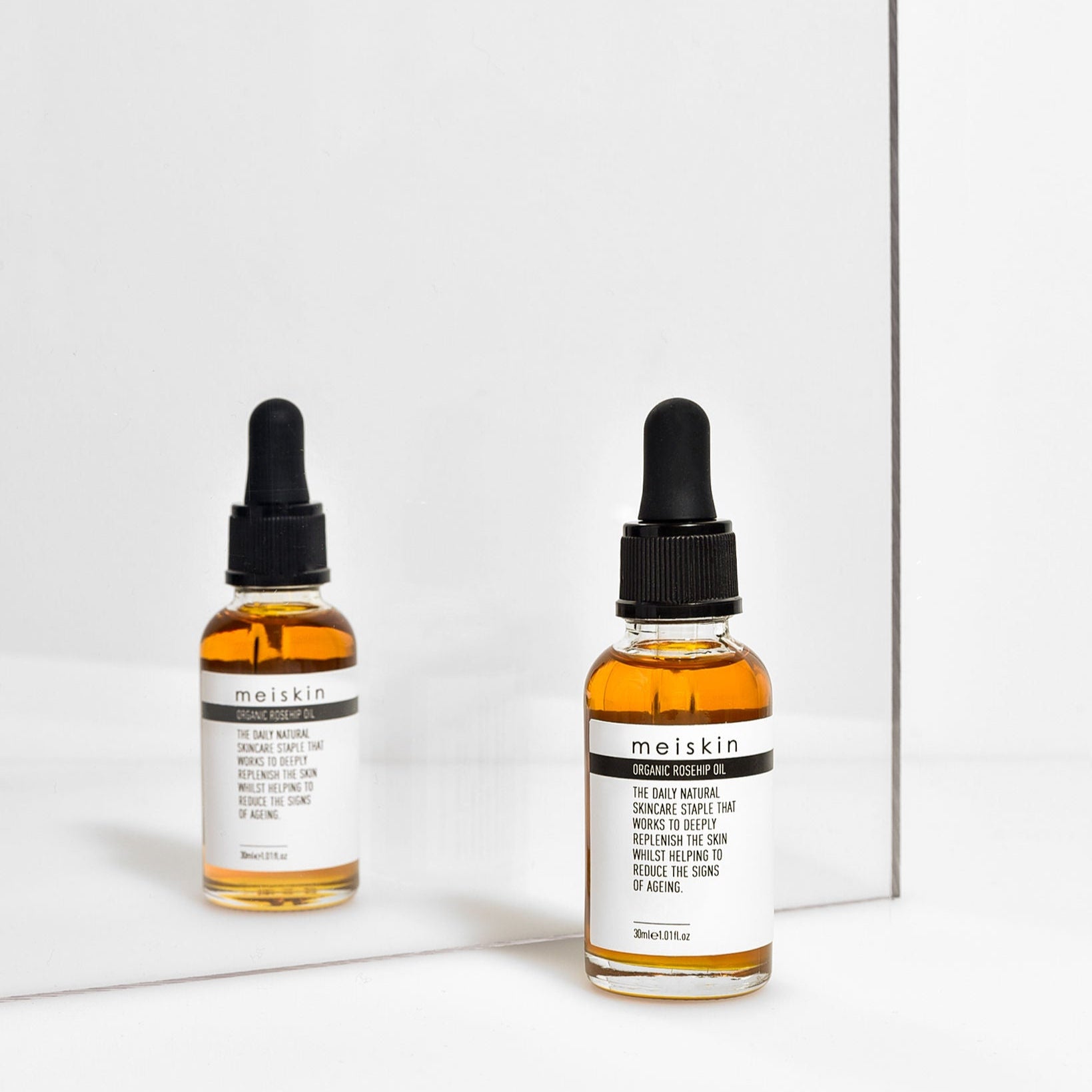 A bottle of Meiskin Organic Rosehip Oil with a dropper, placed in front of a mirror.